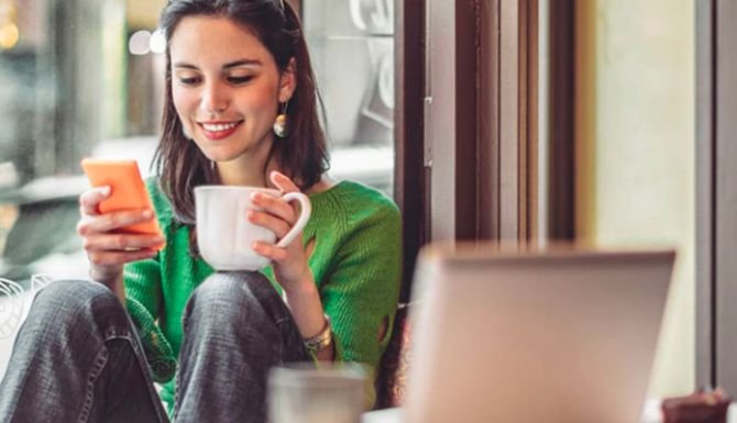 Person on their phone drinking a coffee